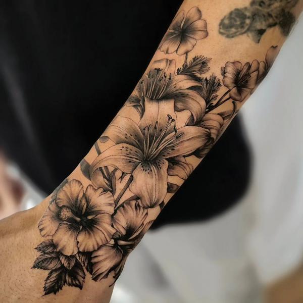 Illustrative lily tattoo on the left inner forearm.