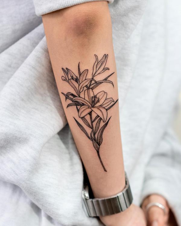 Fine line lily tattoo on outer forearm
