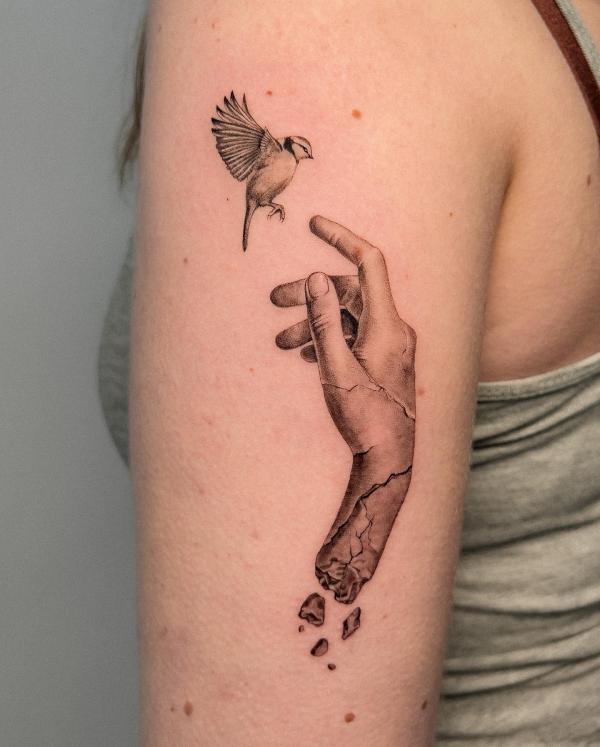 Cracked hand and bird back of arm tattoo