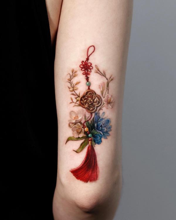 Tassel with flowers back of arm tattoo