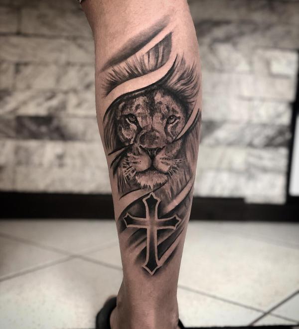 Cross and lion tattoo on calf