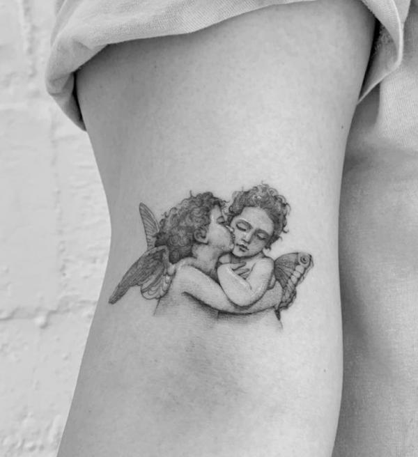 Small kissing cupid tattoo upper arm