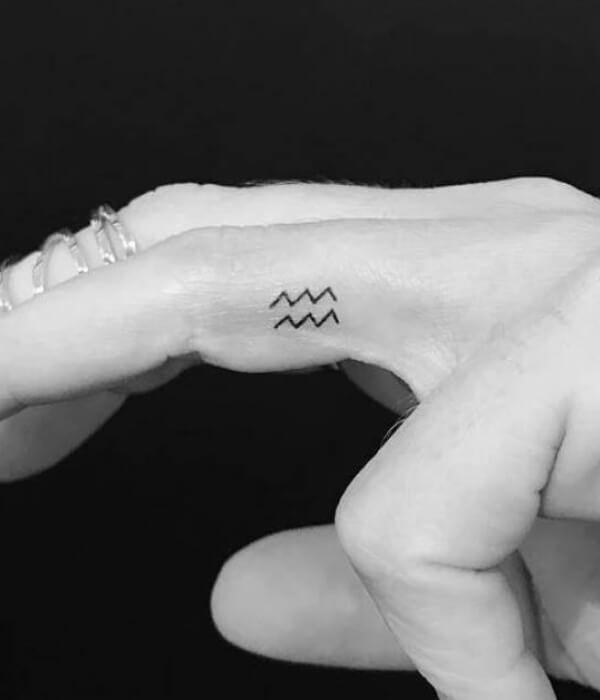 Black Outline Aquarius Symbol Tattoo On Girl Left Hand Finger